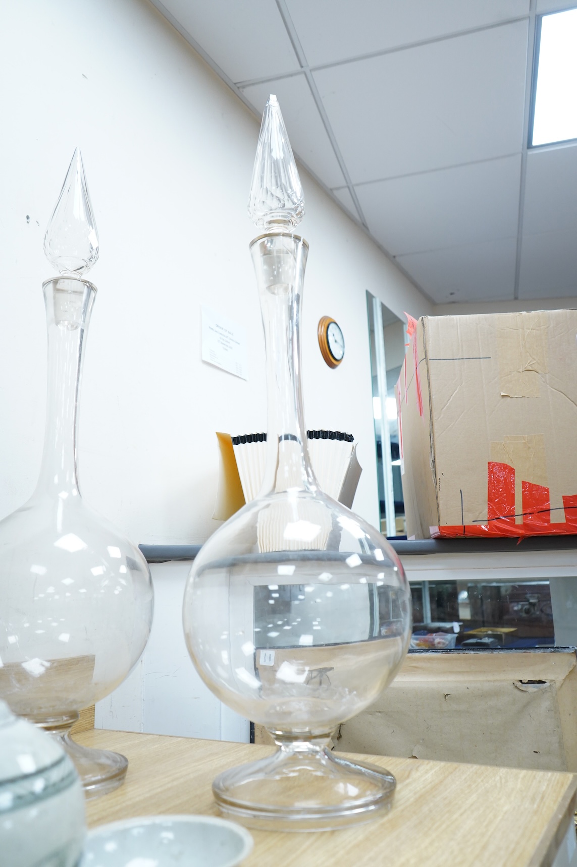 A pair of large clear glass chemist window display bottles and stoppers, one with chip, 90cm high